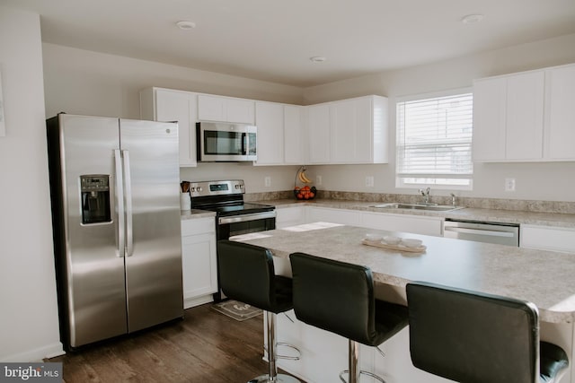 kitchen featuring dark wood-type flooring, a breakfast bar, sink, white cabinetry, and stainless steel appliances