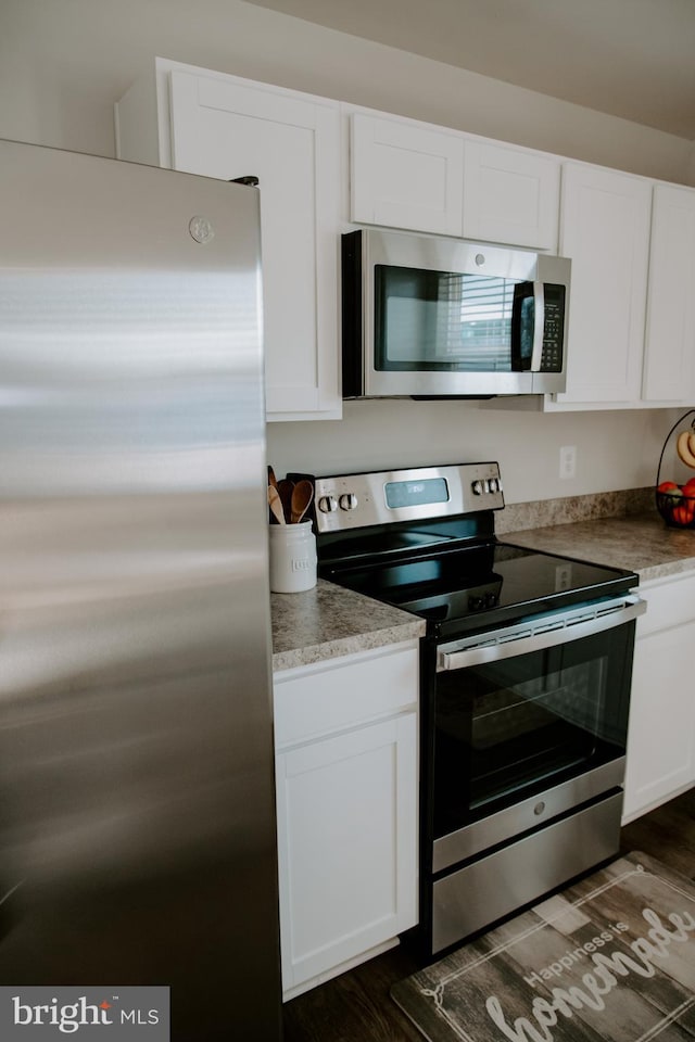 kitchen featuring white cabinetry, stainless steel appliances, and dark hardwood / wood-style flooring