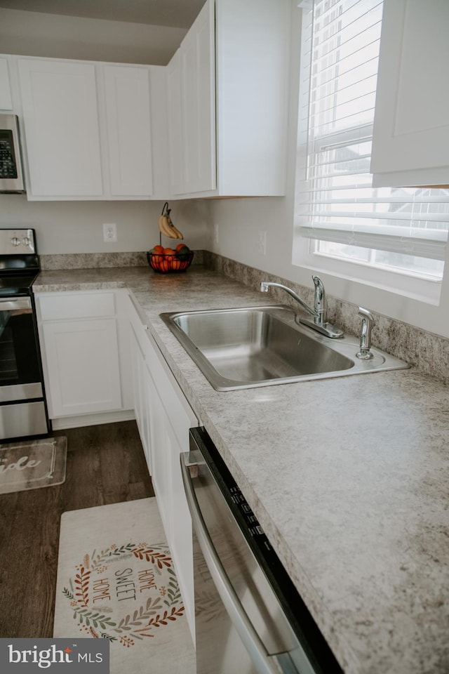 kitchen featuring stainless steel appliances, sink, white cabinets, and dark hardwood / wood-style floors