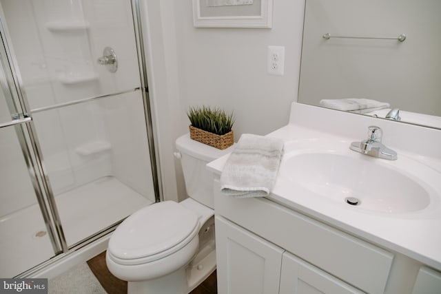 bathroom featuring vanity, toilet, and a shower with door