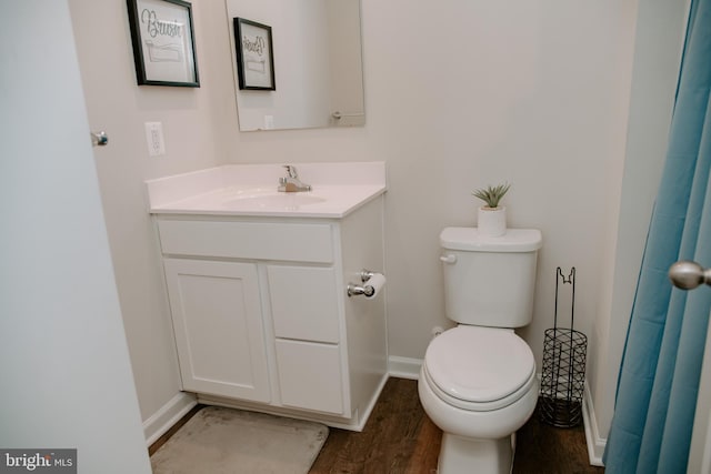 bathroom featuring wood-type flooring, toilet, and vanity