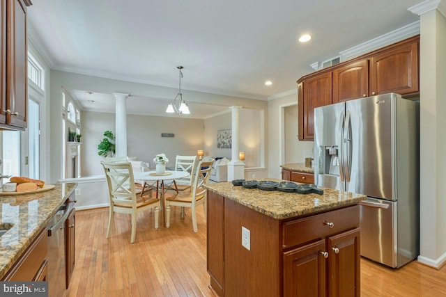 kitchen featuring ornate columns, a kitchen island, appliances with stainless steel finishes, crown molding, and light wood-type flooring