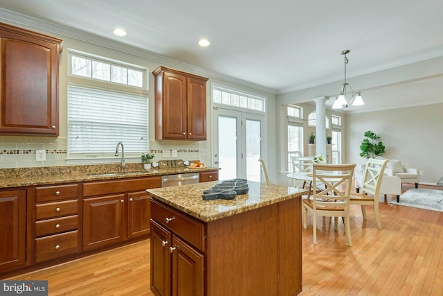 kitchen featuring light wood finished floors, crown molding, decorative columns, and a sink