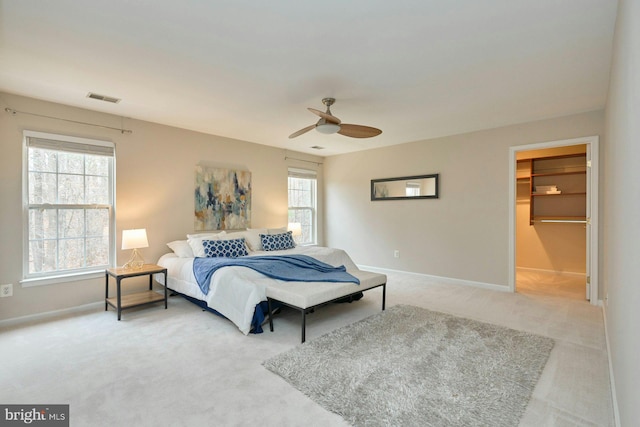 bedroom with visible vents, light carpet, baseboards, and a walk in closet