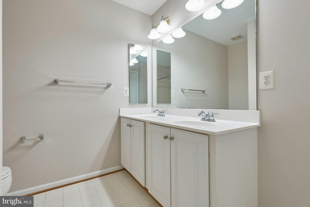 bathroom featuring a sink, baseboards, toilet, and double vanity