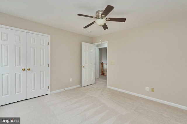 unfurnished bedroom with a closet, light colored carpet, baseboards, and ceiling fan