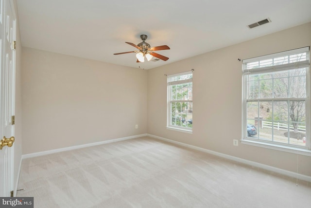 empty room featuring visible vents, light carpet, baseboards, and a ceiling fan