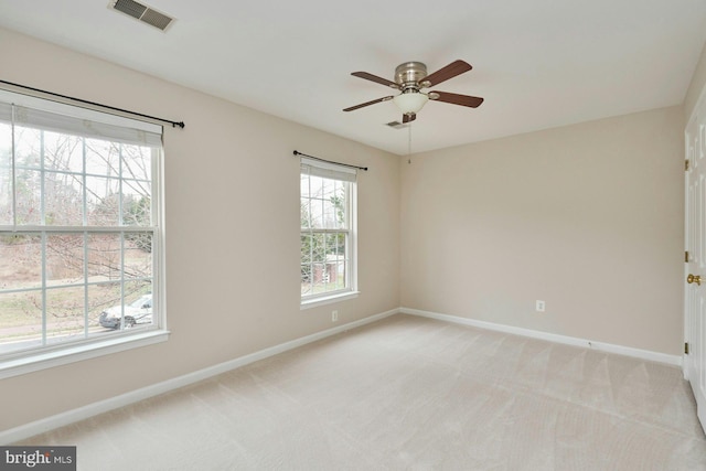 unfurnished room featuring ceiling fan, light colored carpet, visible vents, and baseboards