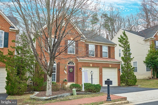 view of front of home featuring a standing seam roof, a garage, aphalt driveway, brick siding, and metal roof