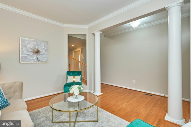 living room with visible vents, wood finished floors, crown molding, and decorative columns