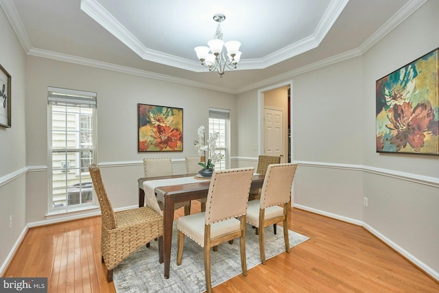 dining room with baseboards, a notable chandelier, ornamental molding, and light wood finished floors