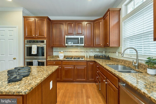 kitchen with backsplash, light stone countertops, ornamental molding, stainless steel appliances, and a sink