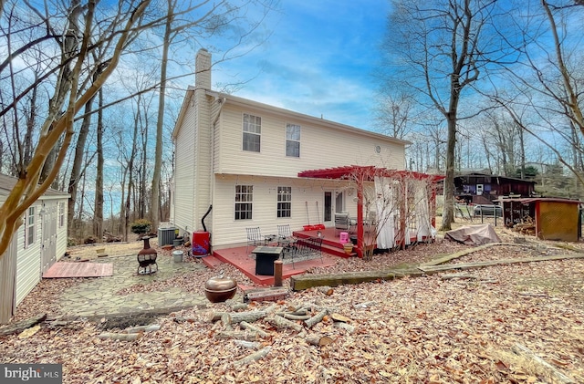 rear view of property featuring a fire pit, a deck, cooling unit, a pergola, and a patio