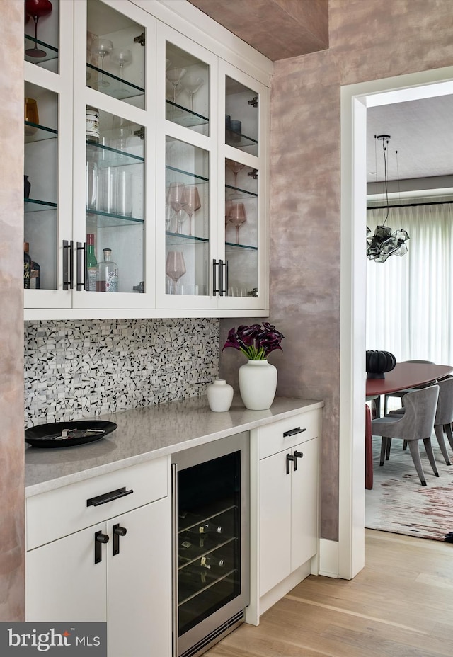 bar with a dry bar, light wood-style floors, wine cooler, and backsplash