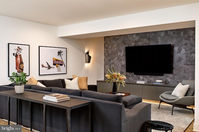 living room featuring wallpapered walls, an accent wall, and wood finished floors