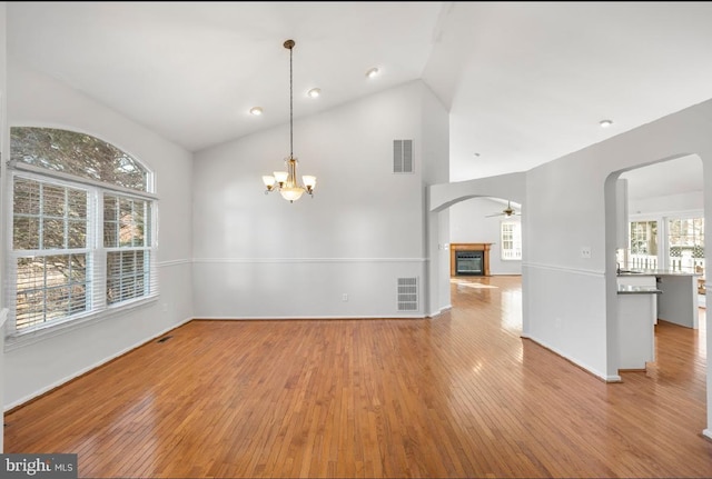 interior space with high vaulted ceiling, ceiling fan with notable chandelier, and light wood-type flooring