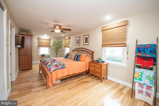 bedroom with multiple windows, ceiling fan, and light wood-type flooring