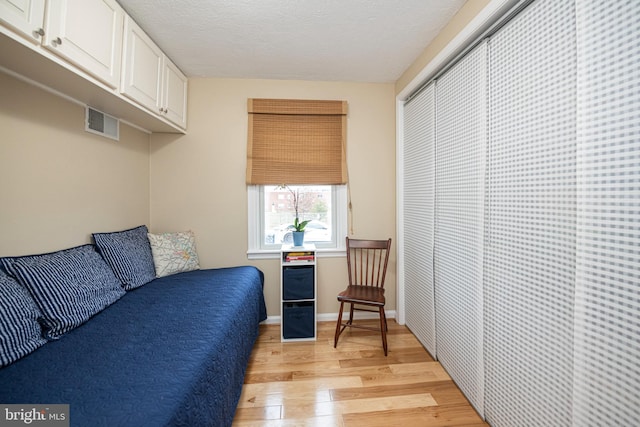 bedroom featuring light hardwood / wood-style flooring, a closet, and a textured ceiling