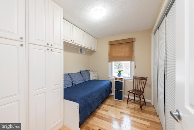 bedroom with a textured ceiling and light hardwood / wood-style floors