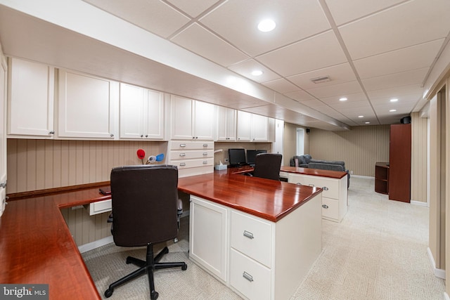 carpeted office space with a paneled ceiling and built in desk