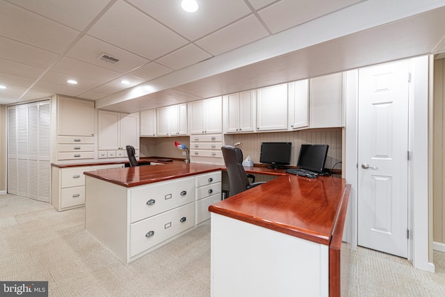 office with light colored carpet, built in desk, and a paneled ceiling