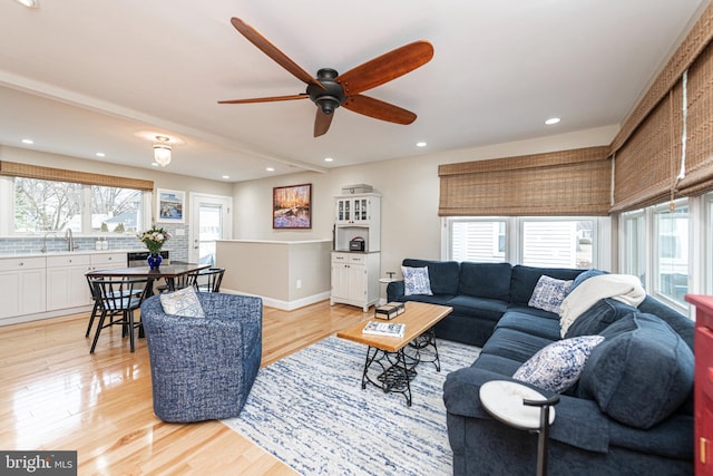 living room with plenty of natural light, sink, and light hardwood / wood-style floors