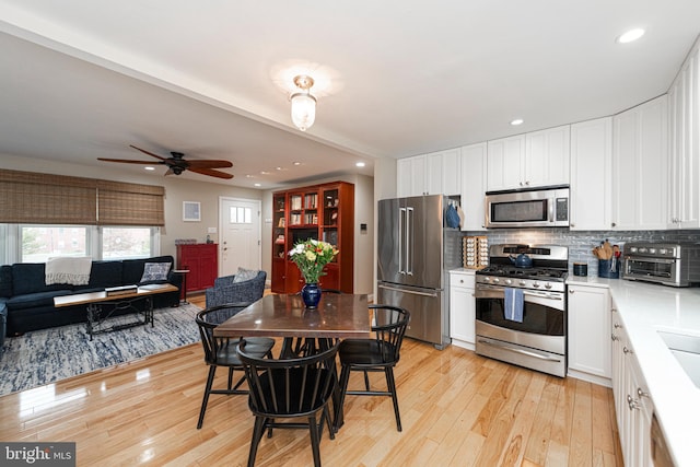 kitchen featuring ceiling fan, white cabinetry, backsplash, stainless steel appliances, and light hardwood / wood-style floors