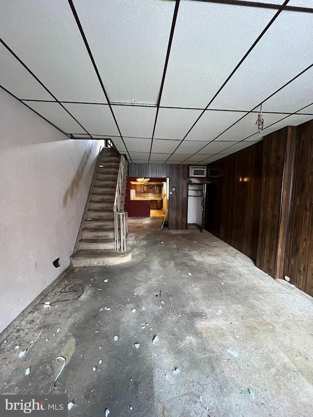 basement with a paneled ceiling and wooden walls