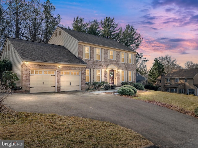 colonial house with a garage and a yard