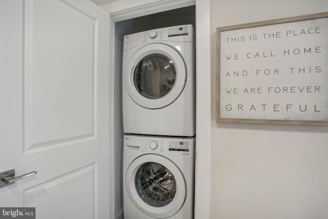 clothes washing area featuring stacked washer and clothes dryer