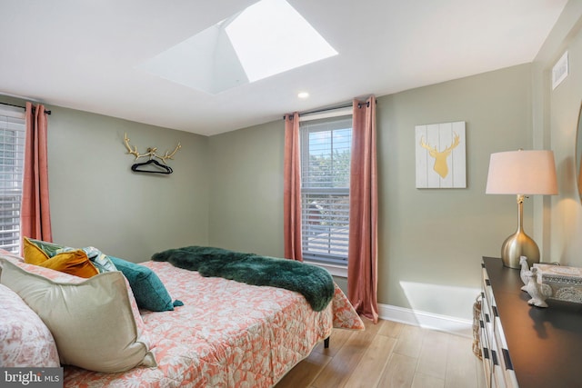 bedroom with light wood-type flooring and a skylight