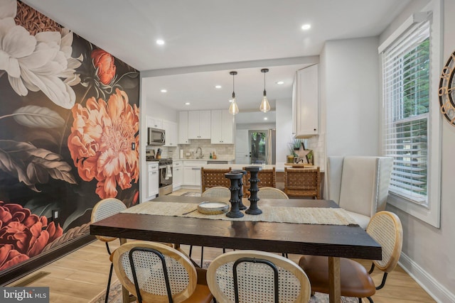 dining area with a healthy amount of sunlight, sink, and light hardwood / wood-style floors