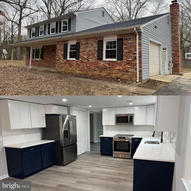 kitchen with sink, blue cabinetry, appliances with stainless steel finishes, white cabinetry, and light hardwood / wood-style floors