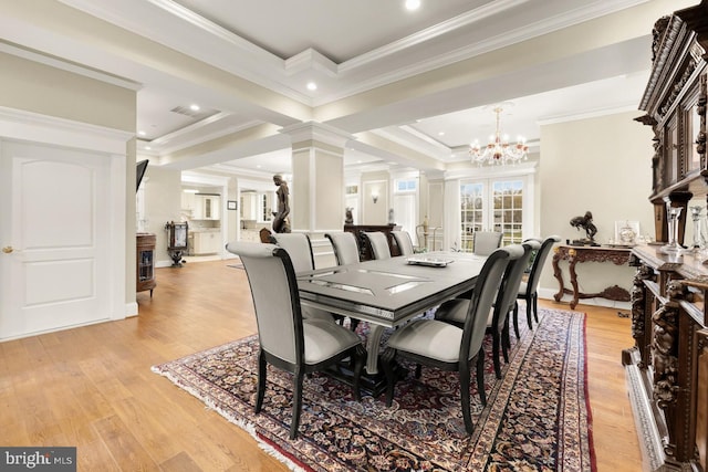 dining area featuring a notable chandelier, crown molding, light hardwood / wood-style floors, and ornate columns