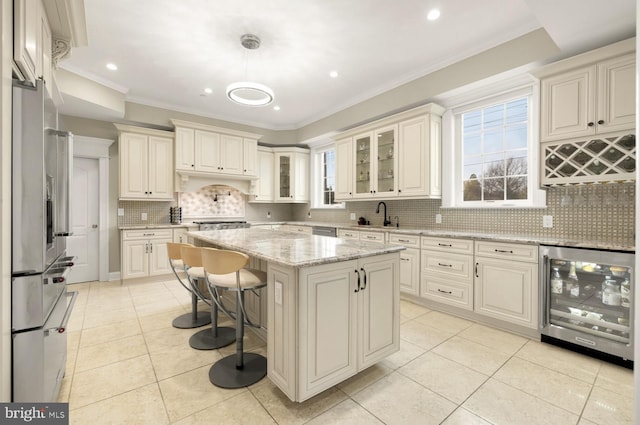 kitchen featuring wine cooler, light stone counters, a kitchen island, pendant lighting, and stainless steel appliances