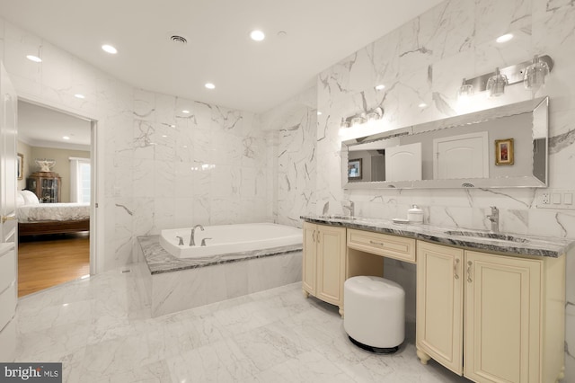 bathroom with vanity, tile walls, and a relaxing tiled tub