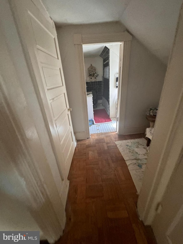 corridor featuring vaulted ceiling and dark parquet flooring