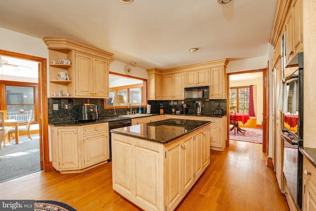 kitchen with plenty of natural light, a center island, decorative backsplash, and black appliances