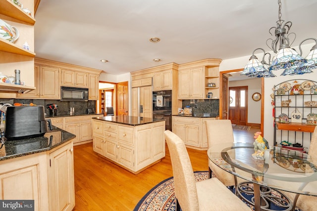 kitchen with hanging light fixtures, black appliances, light hardwood / wood-style floors, and a kitchen island