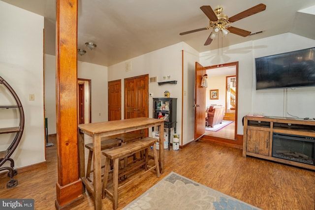 living room with ceiling fan, vaulted ceiling, and light hardwood / wood-style floors