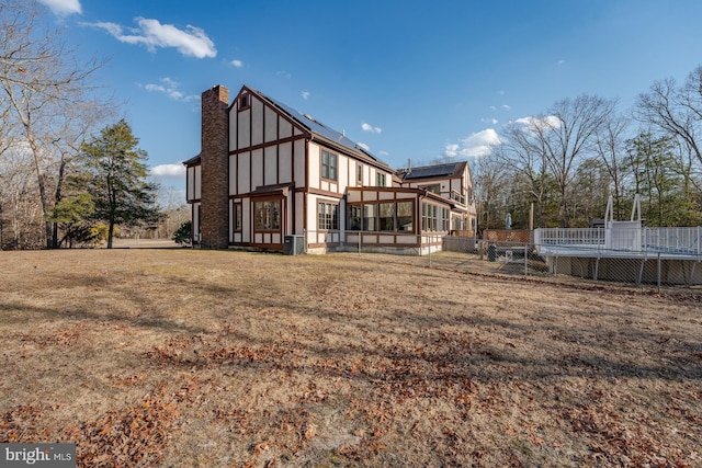 back of house with a lawn and a sunroom