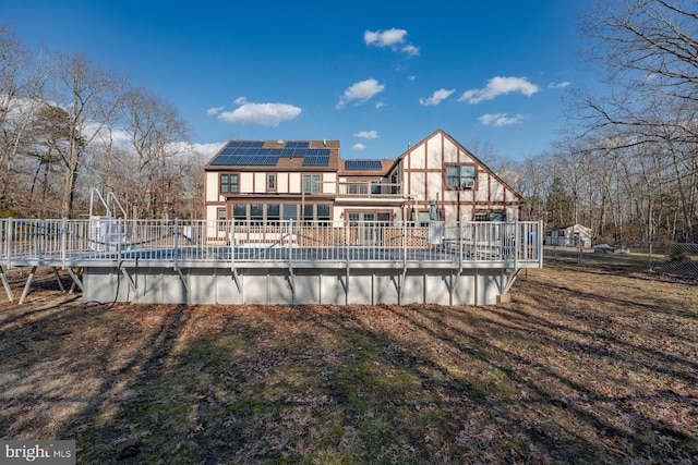 rear view of house featuring a pool side deck and solar panels