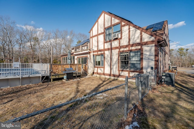 back of property with cooling unit, a deck, solar panels, and central air condition unit