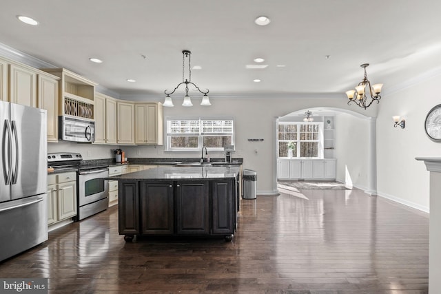 kitchen featuring dark wood-type flooring, cream cabinetry, a kitchen island, stainless steel appliances, and arched walkways