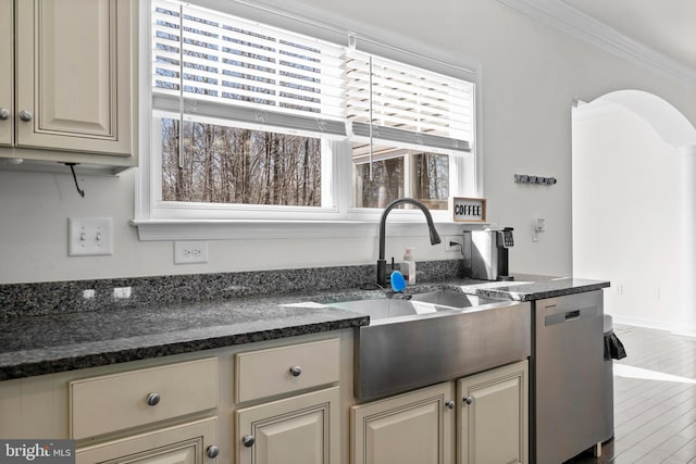 kitchen with ornamental molding, a sink, stainless steel dishwasher, wood finished floors, and arched walkways