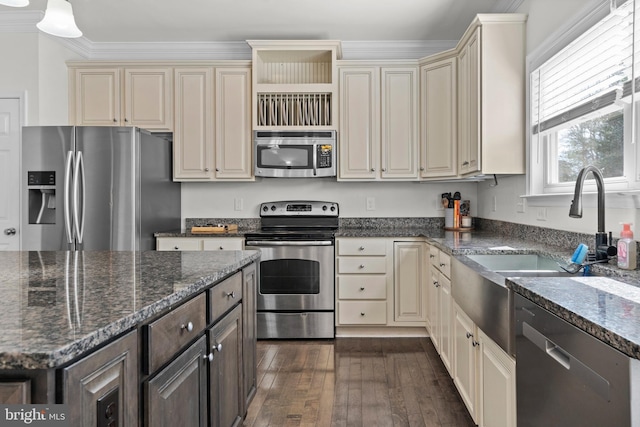 kitchen with dark wood-style floors, dark stone counters, appliances with stainless steel finishes, crown molding, and cream cabinets