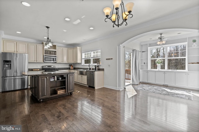 kitchen with stainless steel appliances, arched walkways, cream cabinets, and dark wood-type flooring