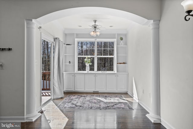 entrance foyer with a ceiling fan, wood-type flooring, arched walkways, decorative columns, and baseboards