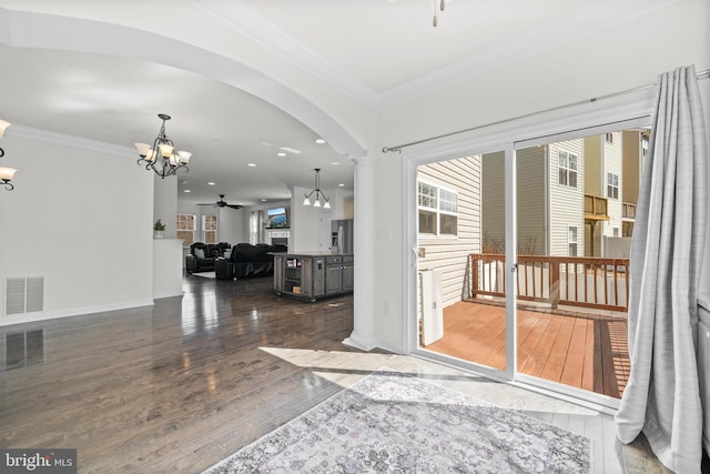 entrance foyer featuring hardwood / wood-style flooring, ceiling fan with notable chandelier, visible vents, and ornamental molding