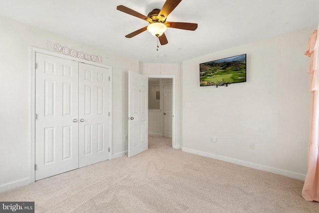 unfurnished bedroom with a ceiling fan, baseboards, a closet, and light carpet